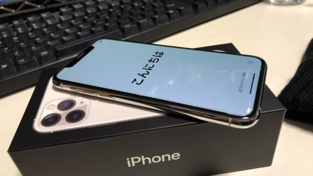 iPhone 11 Pro с приветствения екран на iOS 13 върху кутията на телефона