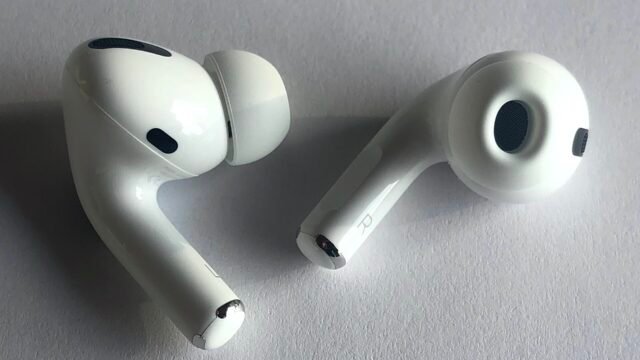 Двете бели слушалки AirPods Pro, поставени върху светла повърхност