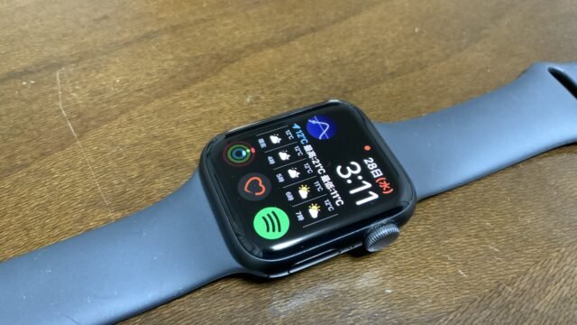 Смарт часовник Apple Watch Series 5 с черна каишка върху дървено бюро