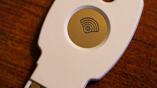 Бял USB ключ за сигурност Google Titan за двуфакторно удостоверяване върху дървена повърхност