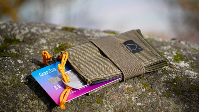 Цветна карта на Revolut, подаваща се от малък текстилен портфейл върху камък