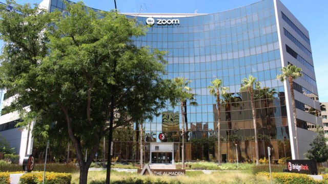 Стъклената сграда на централата на Zoom в Сан Хосе с логото на компанията на фасадата