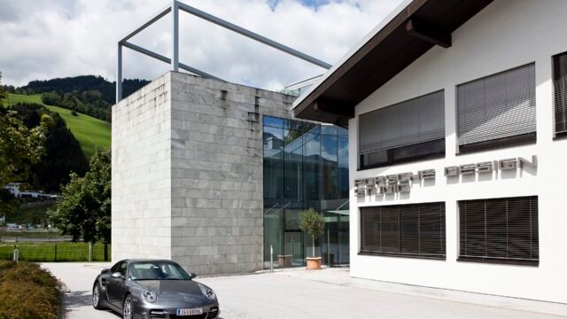Сградата на студиото Porsche Design с паркиран сив Porsche 911 отпред