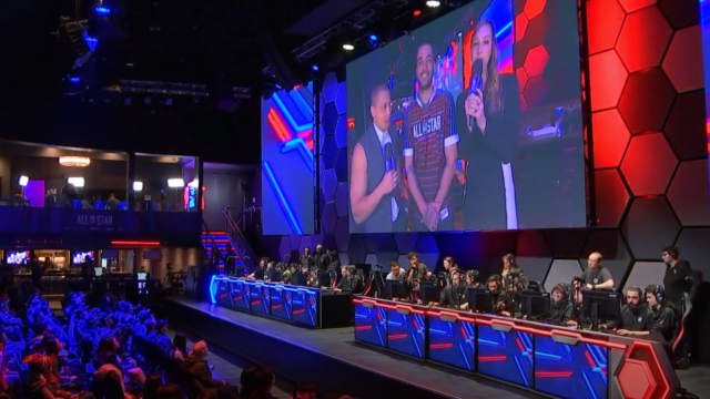 Сцена на турнир по League of Legends с отбори на компютри, голям екран и публика
