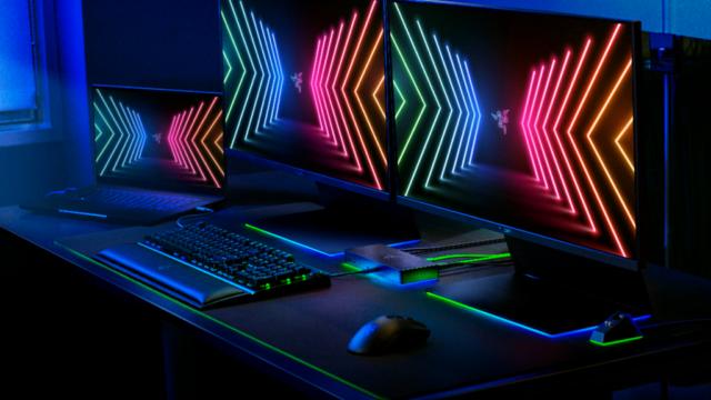Докинг станцията Razer Thunderbolt 4 Dock Chroma на бюро с лаптоп, два монитора, клавиатура и мишка