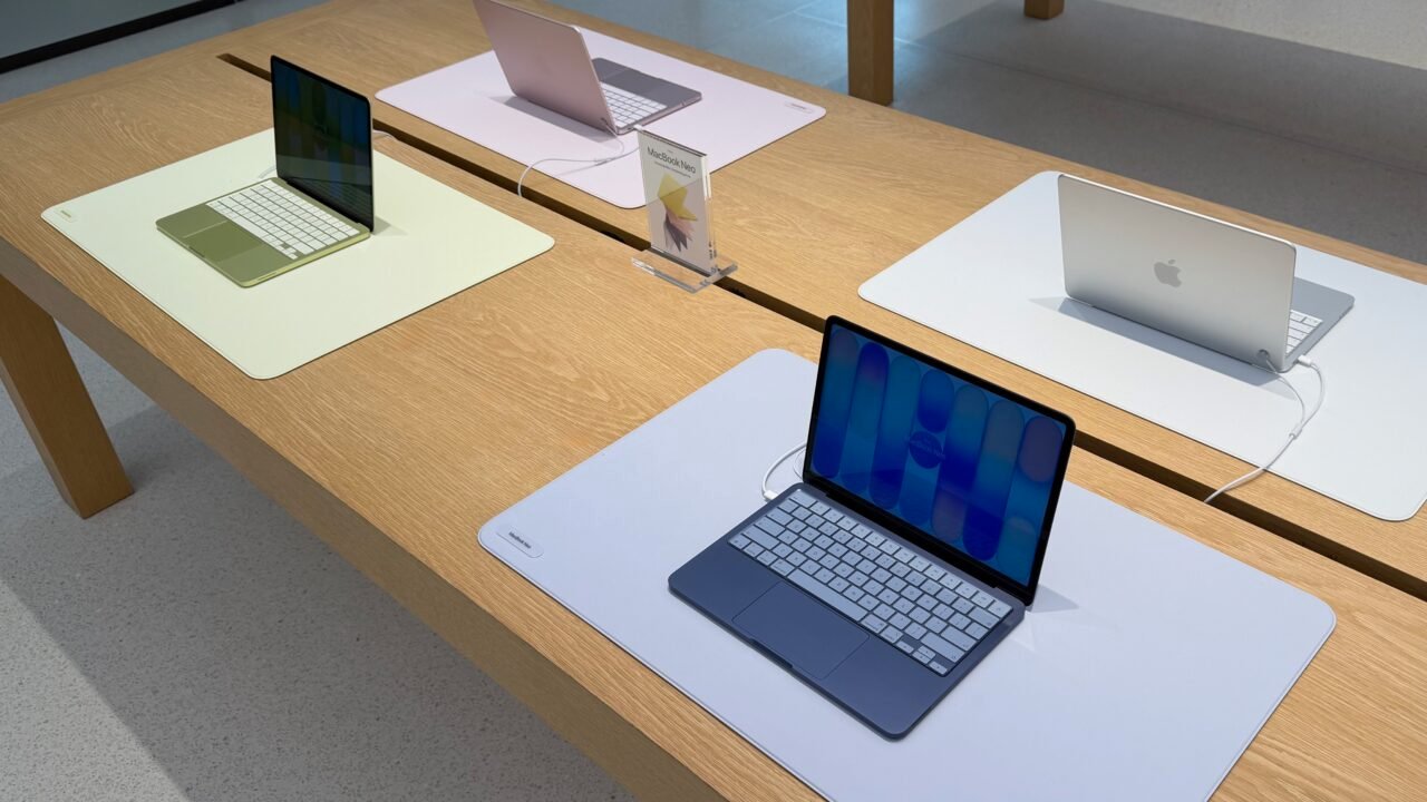 Четири лаптопа MacBook Neo в различни цветове на маса в магазин на Apple