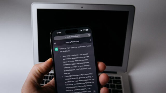 Приложението ChatGPT, отворено на смартфон пред лаптоп – с iCloud плъгините ChatGPT вече стига до пощата и календара