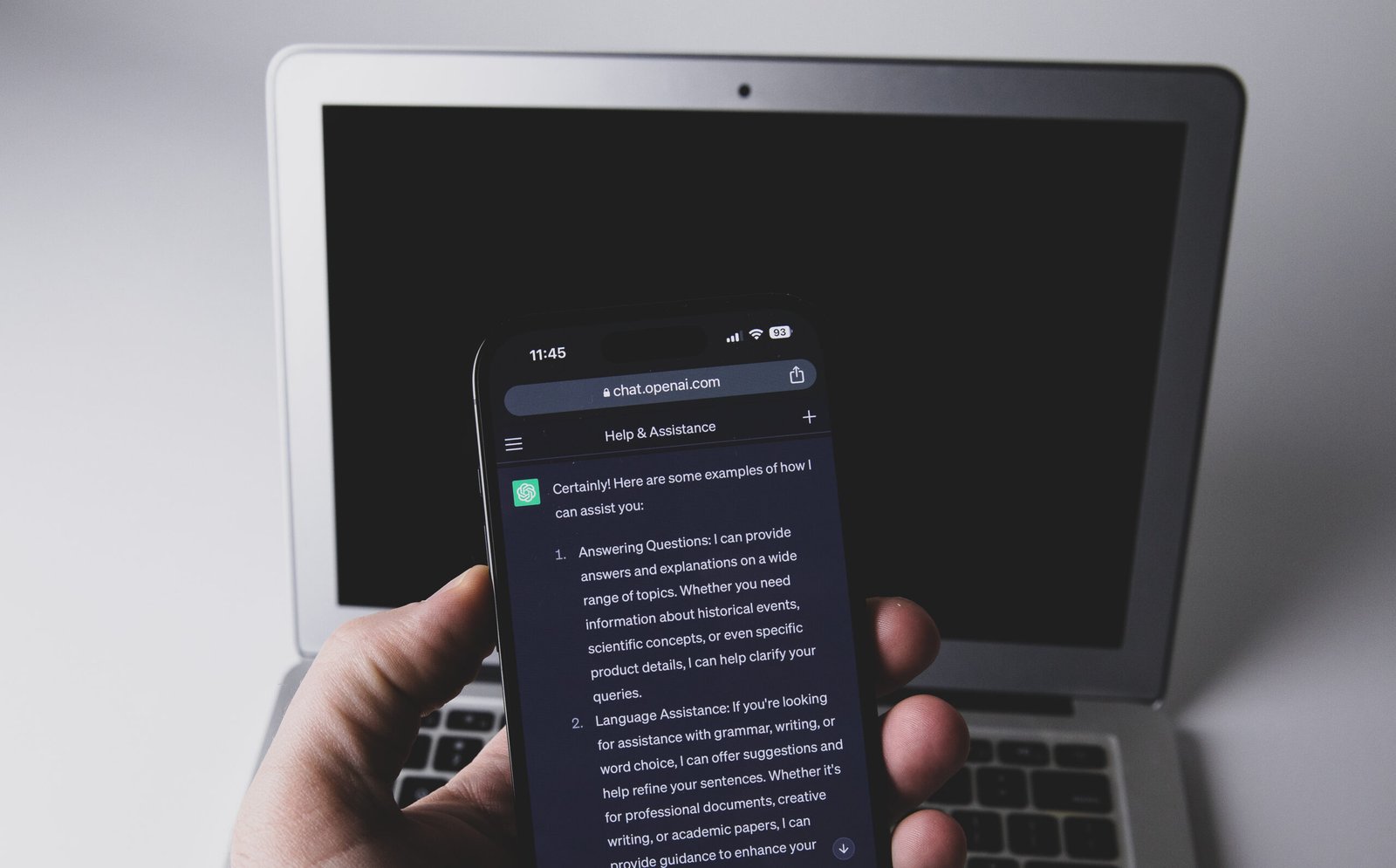 Смартфон с чат в ChatGPT пред лаптоп – заключени чатове в ChatGPT