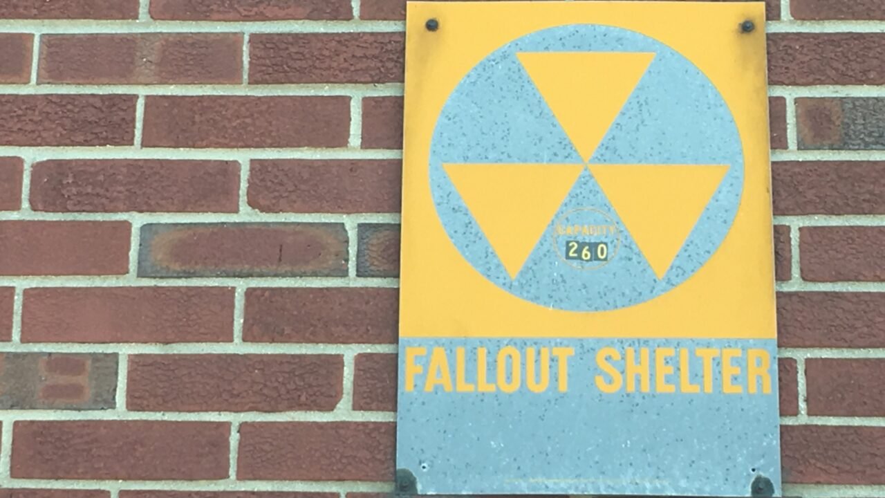 Жълто-син знак „Fallout Shelter“ със символ за радиация на тухлена стена