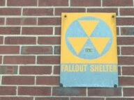 Жълто-син знак „Fallout Shelter“ със символ за радиация на тухлена стена