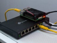 Raspberry Pi 4 в метален корпус върху мрежов суич – типичен сървър за Home Assistant, чиито резервни копия трябва да пазите