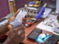 Ръце държат разглобен корпус на смартфон на ремонтен плот – илюстрация за официалните ръководства за ремонт на iPhone Duo