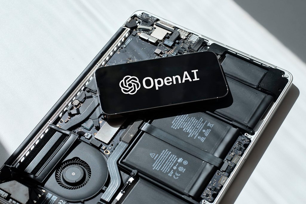 Телефон с логото на OpenAI върху разглобен лаптоп – OpenAI модели в Google Cloud